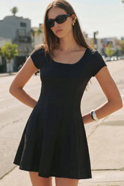Vestido corto de cuello redondo, manga corta, cortes frontales, escote en espalda y corte en a con olanes en bajo. Cierre lateral con cremallera oculta.