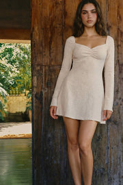 Vestido corto de escote corazón con cortes y plisados decorativos frontales, rib elástico en hombros, manga larga con puño amplio y corte en a. Detalle de textura en tejido y rib rizado en bajo.