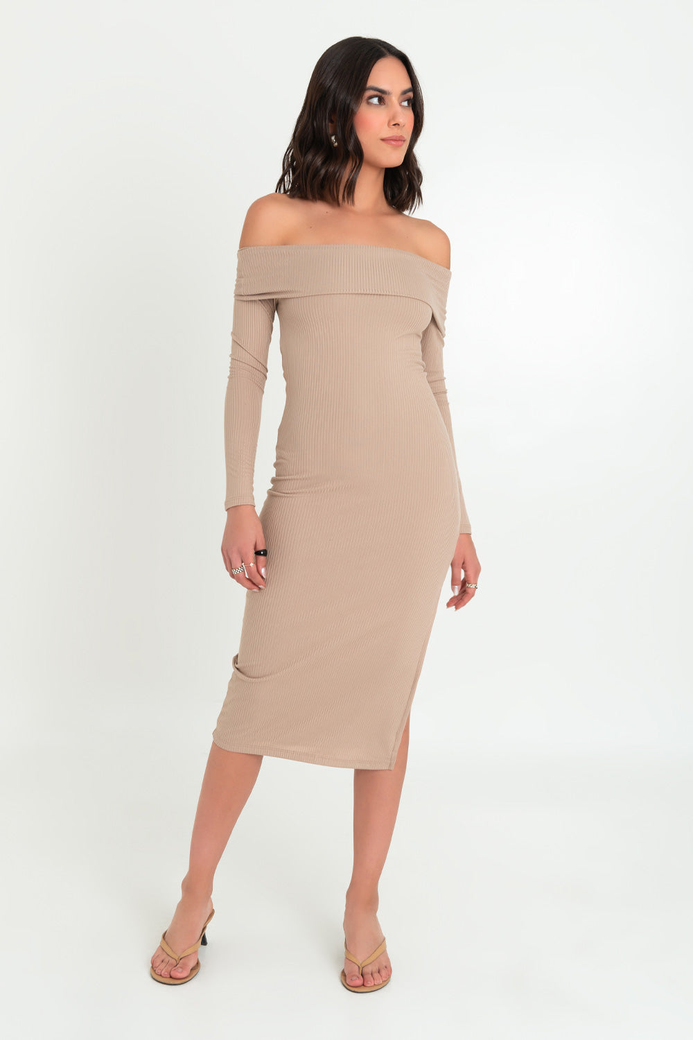 Woman posing in a beige off-the-shoulder midi dress and heeled sandals.