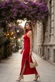 Vestido midi de fit ajustado, sin mangas, escote en espalda y cuello alto halter. Detalle de plisados en costados, abertura lateral en bajo, cierre posterior con botón y ojal.