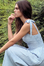 Vestido midi de estampado cuadros, tirantes con nudo amarrable, escote recto con cortes y plisados decorativos, corte en a, plisados en cintura con corte frontal en v y fruncido en espalda.