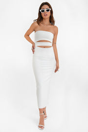 Vestido midi de fit ajustado, strapless, escote recto y detalle de cut outs frontales. Cierre posterior con cremallera visible en contraste y abertura en bajo.
