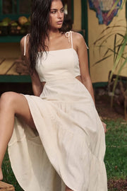 Vestido midi de lino, corte en a, tirantes delgados con nudo amarrable, bajo con capas de olanes, cut out en costados y espalda. Detalle de rib elástico en cintura y fruncido en espalda.