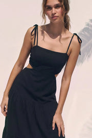 Vestido midi de lino, corte en a, tirantes delgados con nudo amarrable, bajo con capas de olanes, cut out en costados y espalda. Detalle de rib elástico en cintura y fruncido en espalda. 