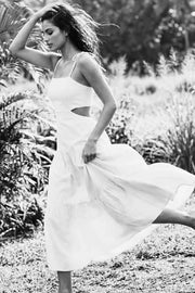 Vestido midi de lino, corte en a, tirantes delgados con nudo amarrable, bajo con capas de olanes, cut out en costados y espalda. Detalle de rib elástico en cintura y fruncido en espalda.