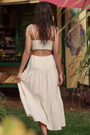 Vestido midi de lino, corte en a, tirantes delgados con nudo amarrable, bajo con capas de olanes, cut out en costados y espalda. Detalle de rib elástico en cintura y fruncido en espalda.