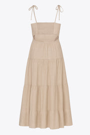 Vestido midi de lino, corte en a, tirantes delgados con nudo amarrable, bajo con capas de olanes, cut out en costados y espalda. Detalle de rib elástico en cintura y fruncido en espalda.