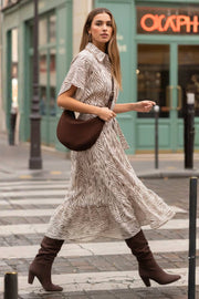 Vestido midi camisero, estampado, de fit fluido, manga corta amplia con olanes, cuello camisero, cinturón amarrable del mismo tejido, pinza de amplitud en espalda y olanes en bajo asimétrico. Detalle de bies en contraste.