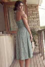 Vestido midi de bordado floral, cuello halter con rib elástico, sin mangas, escote recto, cortes frontales, detalle frontal v en cintura con plisados y fruncido en espalda.