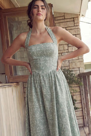 Vestido midi de bordado floral, cuello halter con rib elástico, sin mangas, escote recto, cortes frontales, detalle frontal v en cintura con plisados y fruncido en espalda.