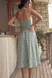 Vestido midi de bordado floral, cuello halter con rib elástico, sin mangas, escote recto, cortes frontales, detalle frontal v en cintura con plisados y fruncido en espalda.