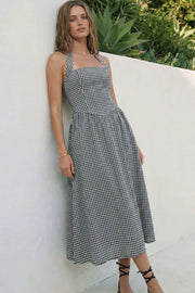 Vestido midi de estampado cuadros, cuello halter con rib elástico, sin mangas, escote recto, cortes frontales, detalle frontal v en cintura con plisados y fruncido en espalda.