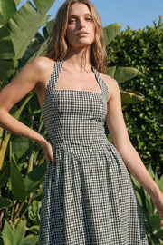 Vestido midi de estampado cuadros, cuello halter con rib elástico, sin mangas, escote recto, cortes frontales, detalle frontal v en cintura con plisados y fruncido en espalda.