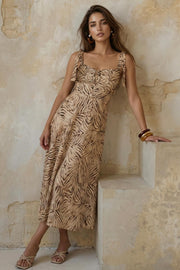 Vestido midi estampado de tirantes con nudo amarrable, escote corazón con plisados y cortes decorativos frontales, corte en a y cierre posterior con cremallera oculta.