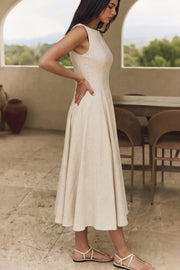 Vestido midi de lino, sin mangas, corte en a, cuello barco, escote en espalda y cortes frontales decorativos. Cierre lateral con cremallera oculta.