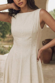Vestido midi de lino, sin mangas, corte en a, cuello barco, escote en espalda y cortes frontales decorativos. Cierre lateral con cremallera oculta.