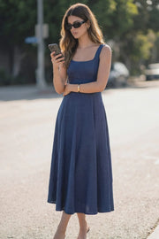 Vestido midi, sin mangas, corte en a, escote cuadrado y cortes decorativos. Cierre lateral con cremallera oculta.