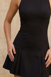 Vestido corto de fit ajustado, cuello redondo, sin mangas, cortes frontales, corte en a y bajo tableado. Cierre posterior con cremallera oculta.