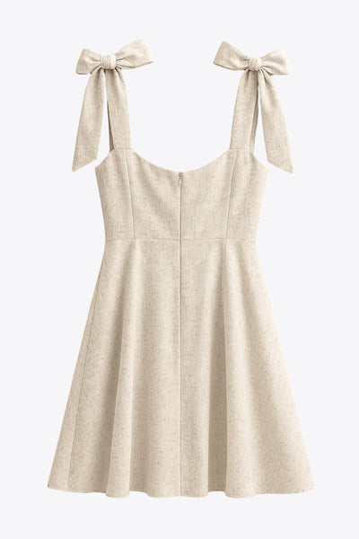 Vestido corto de tirantes con nudo amarrable, escote corazón con cortes y plisados, fit ajustado, corte en a y cierre posterior con cremallera oculta.