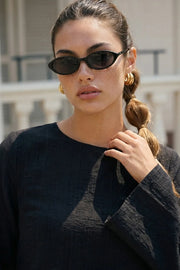 Túnica de manga larga con puño amplio, cuello redondo, bajo frontal asimétrico, corte en a, cierre posterior con botón y ojal.