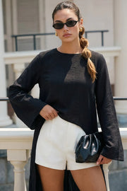 Túnica de manga larga con puño amplio, cuello redondo, bajo frontal asimétrico, corte en a, cierre posterior con botón y ojal.