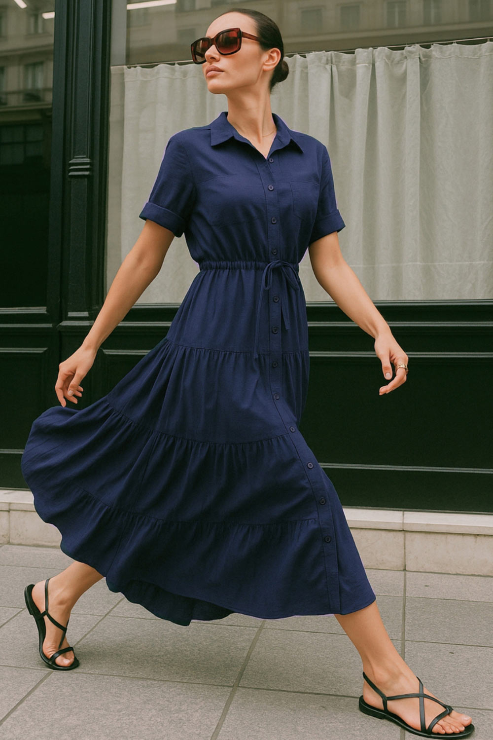 Maxi vestido camisero de manga corta con doblez en borde, cuello camisero, plisados frontales, olanes en bajo, jareta ajustable en cintura y cierre frontal con hilera de botones.