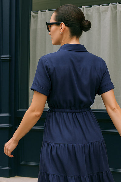 Maxi vestido camisero de manga corta con doblez en borde, cuello camisero, plisados frontales, olanes en bajo, jareta ajustable en cintura y cierre frontal con hilera de botones.