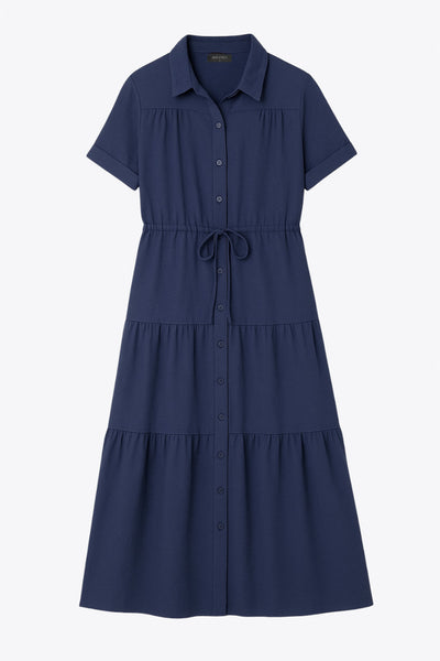 Maxi vestido camisero de manga corta con doblez en borde, cuello camisero, plisados frontales, olanes en bajo, jareta ajustable en cintura y cierre frontal con hilera de botones.