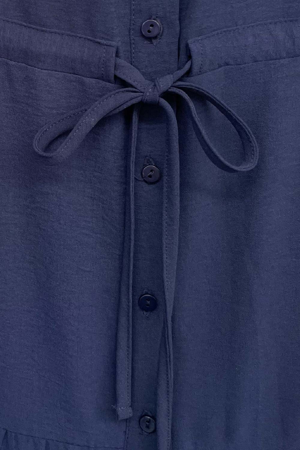 Maxi vestido camisero de manga corta con doblez en borde, cuello camisero, plisados frontales, olanes en bajo, jareta ajustable en cintura y cierre frontal con hilera de botones.