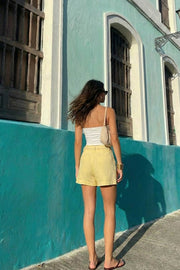 Top strapless satinado de escote corazón con nudo, plisados decorativos en costados y abertura frontal con bajo asimétrico. Rib rizado en borde de bajo.