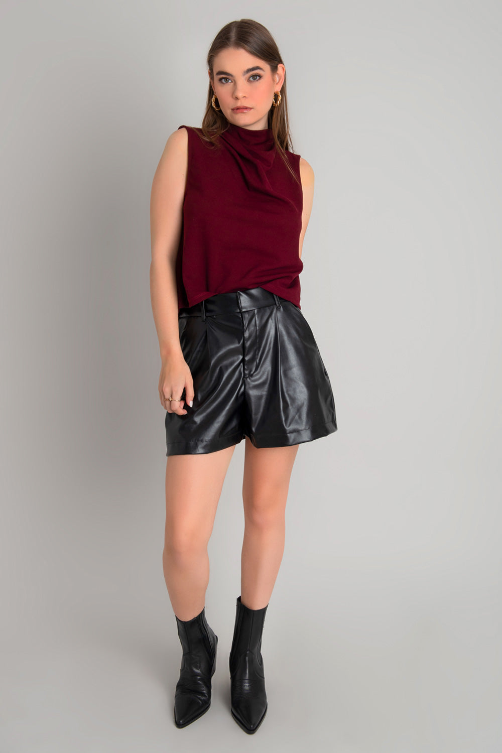 Blusa sin mangas de fit recto, cuello mock con detalles plisados y cierre posterior con botón y ojal.