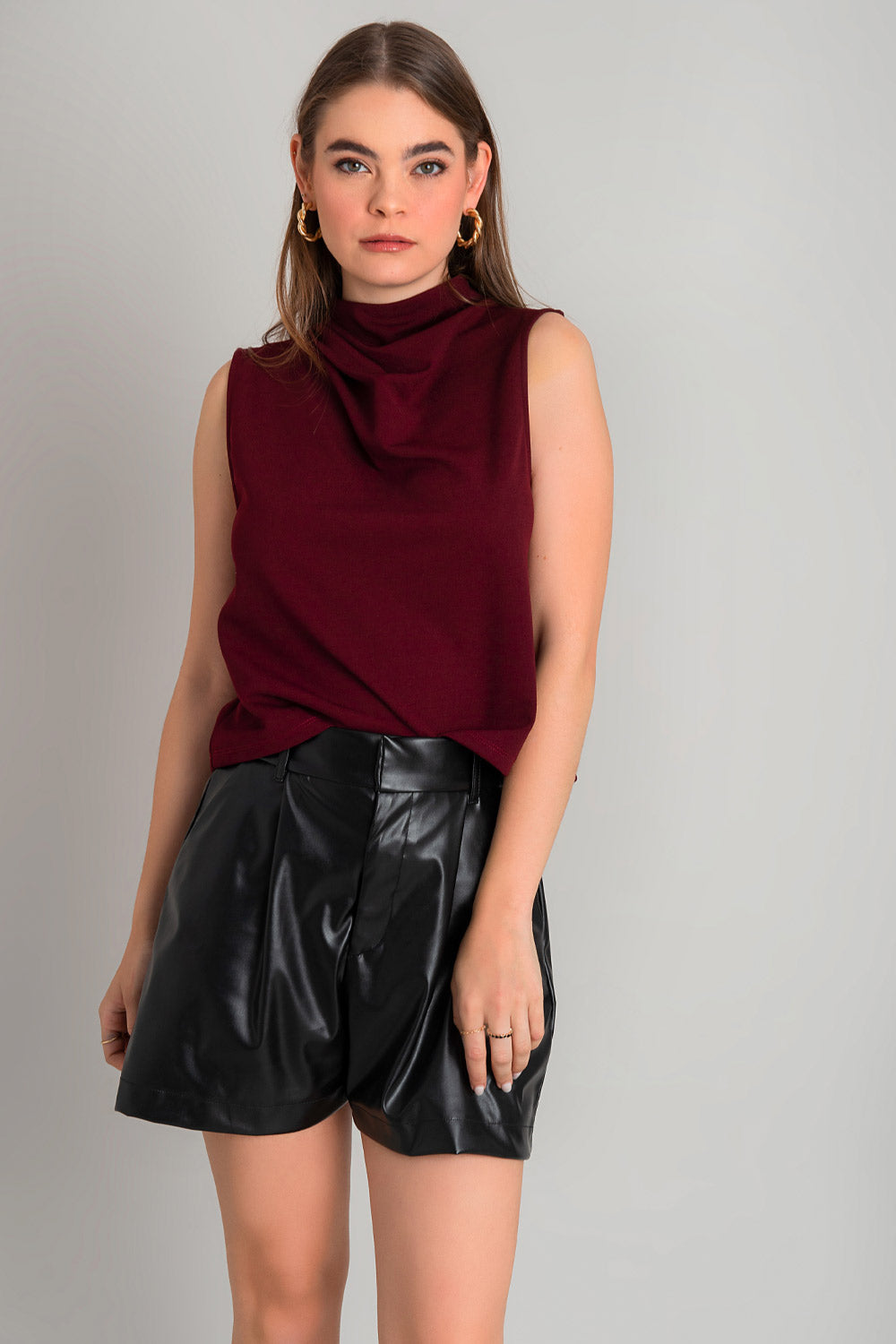 Blusa sin mangas de fit recto, cuello mock con detalles plisados y cierre posterior con botón y ojal.