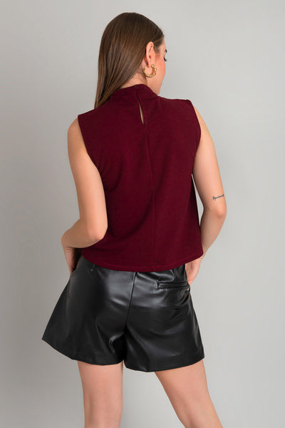 Blusa sin mangas de fit recto, cuello mock con detalles plisados y cierre posterior con botón y ojal.